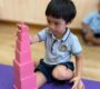 A child carefully stacking pink blocks on a purple mat in a classroom Starshine Montessori 90x80