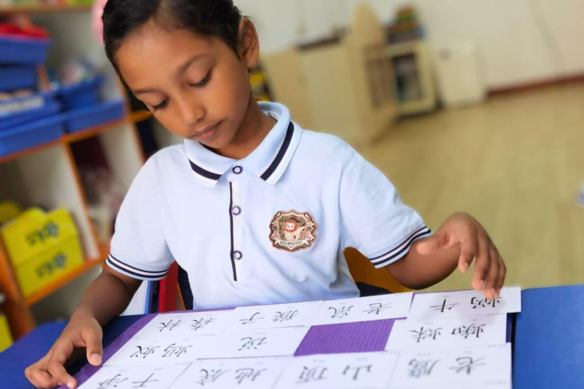 Child focusing on a sheet of paper with rows of written chinese characters