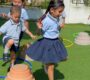 Preschoolers in uniforms playing with hoops and cones on green turf at Starshine Montessori showcasing outdoor learning activities Starshine Montessori 90x80