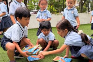 Group of young children working together on a puzzle during an outdoor learning activity at Starshine Montessori preschool, enhancing teamwork and collaboration skills.