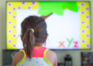 Child watching an educational video, engaging in early learning through interactive screen time in a home environment.