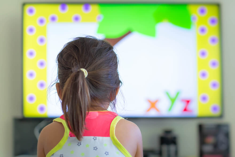 Child watching an educational video, engaging in early learning through interactive screen time in a home environment.