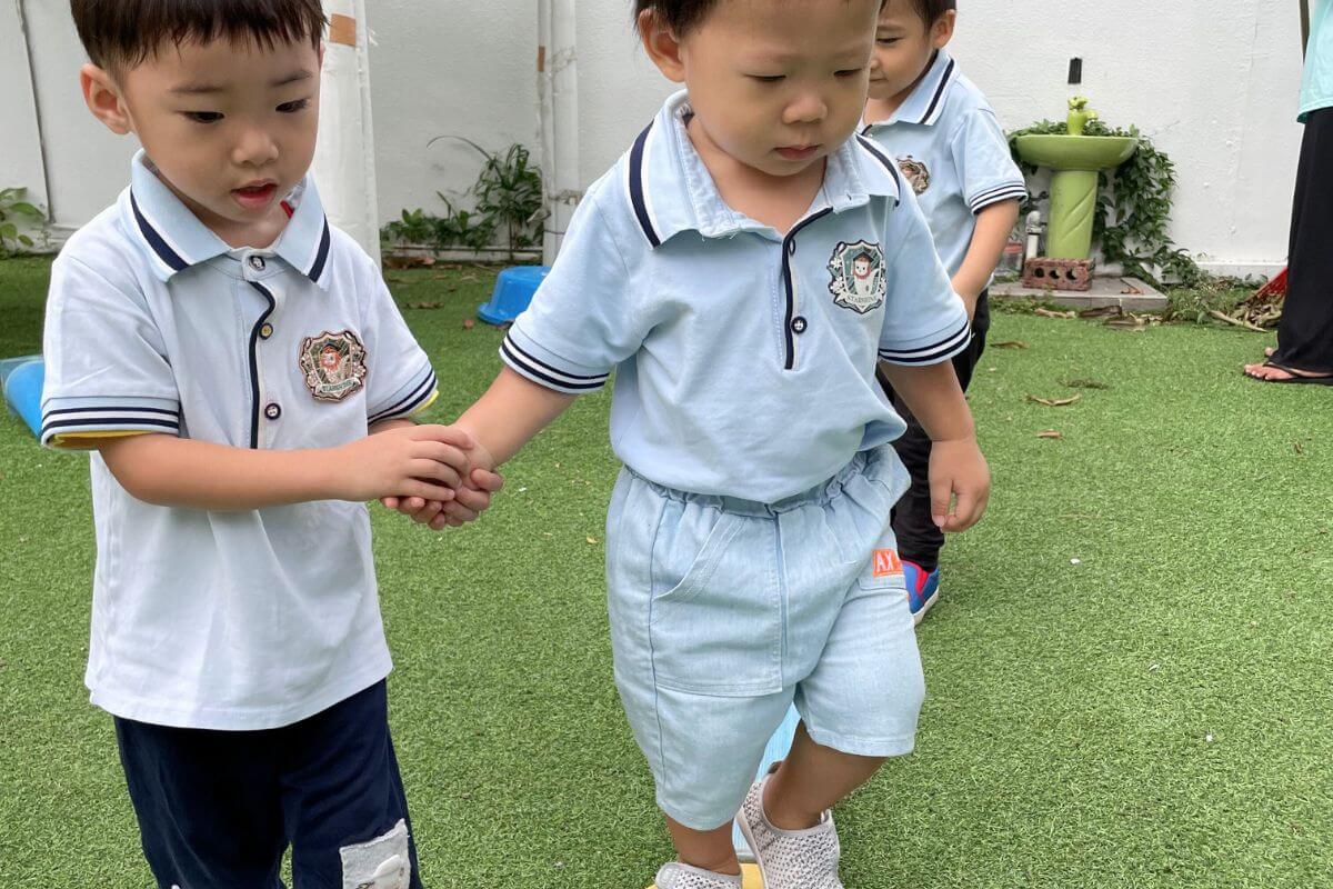 Young children holding hands during an outdoor preschool activity, fostering teamwork, support, and social development at Starshine Montessori.