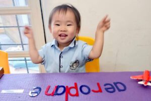 Happy child engaging in a preschool activity with letters, building early literacy skills in a joyful learning environment at Starshine Montessori.