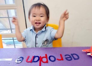 Happy child engaging in a preschool activity with letters, building early literacy skills in a joyful learning environment at Starshine Montessori.