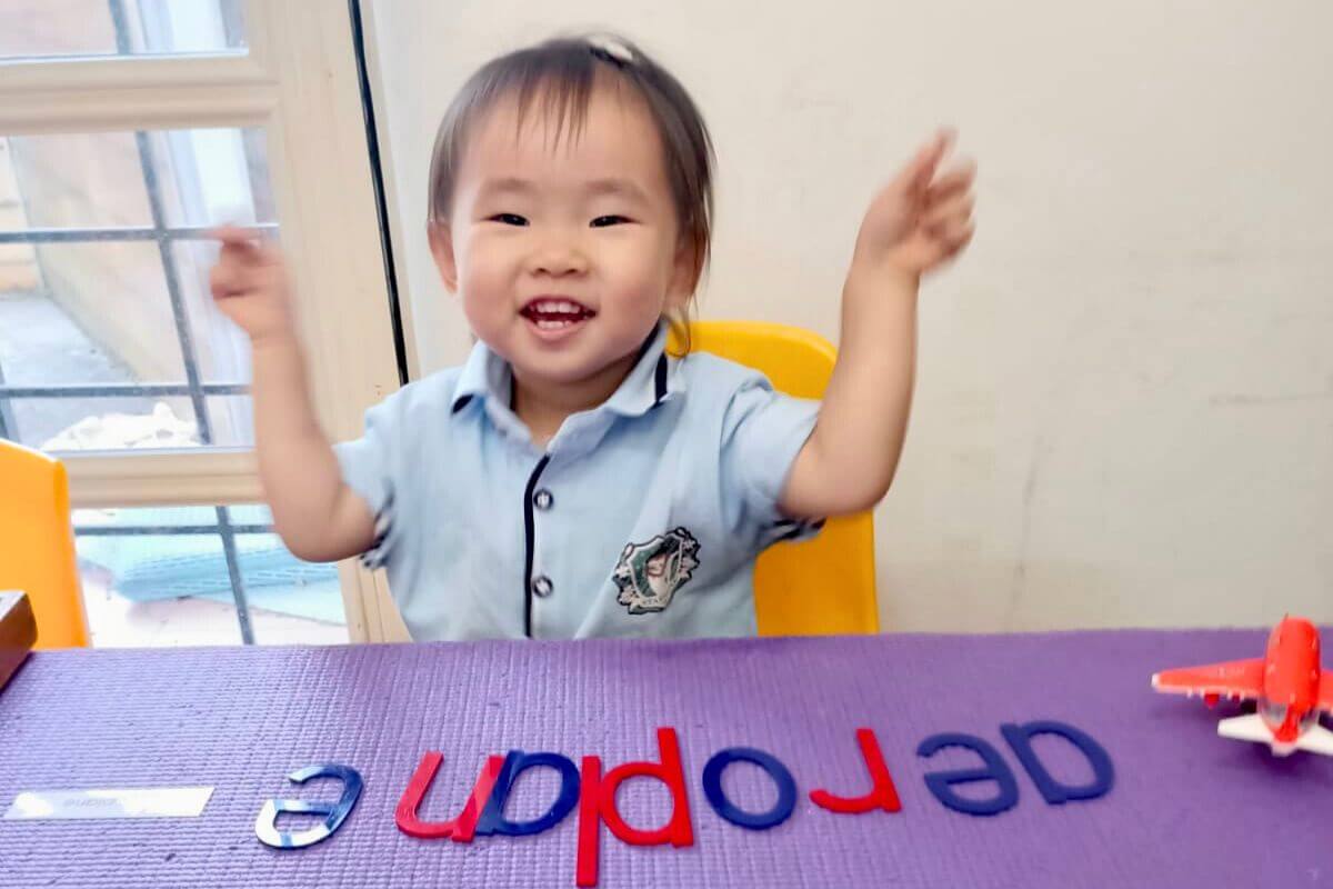 Happy child engaging in a preschool activity with letters, building early literacy skills in a joyful learning environment at Starshine Montessori.