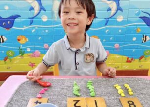 A smiling preschooler engaging in a Montessori-inspired activity with colorful materials and a marine-themed background at Starshine Montessori.