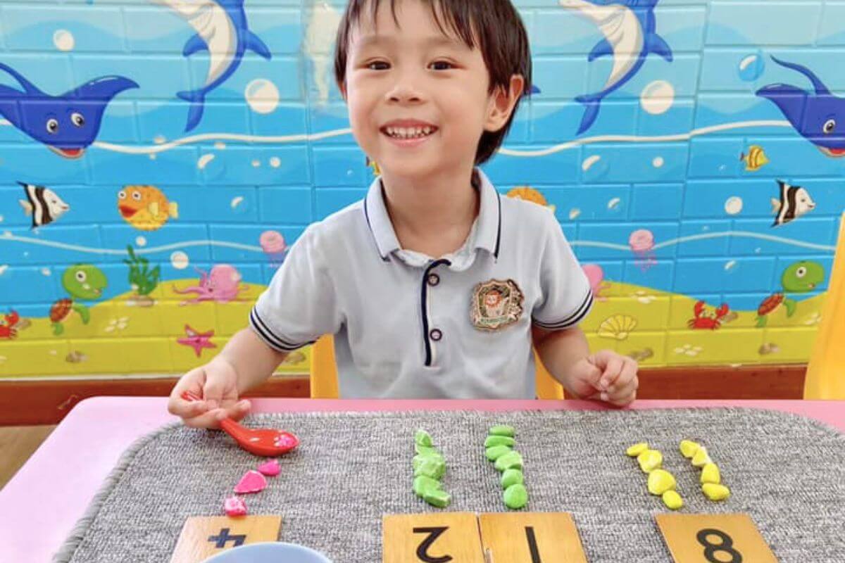 A smiling preschooler engaging in a Montessori-inspired activity with colorful materials and a marine-themed background at Starshine Montessori.