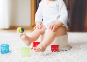 Toddler sitting on a potty, engaging in early potty training to learn independence and personal care skills.