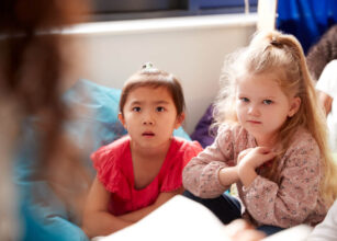 Young children listening attentively during story time in a preschool setting, fostering focus and language skills through storytelling.