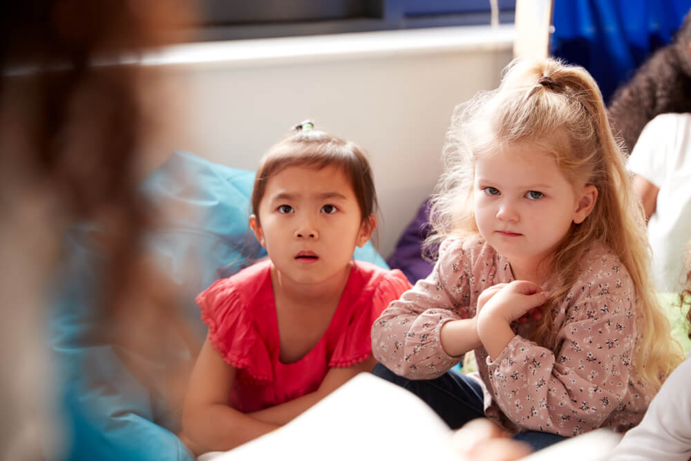 Young children listening attentively during story time in a preschool setting, fostering focus and language skills through storytelling.