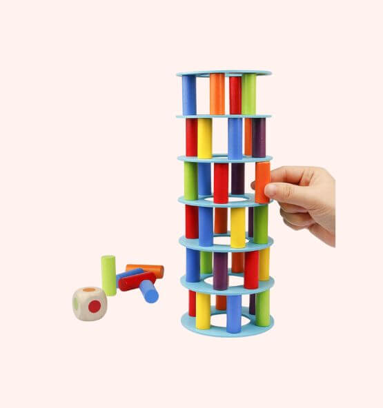 A colorful stacking and balancing toy consisting of wooden discs and cylindrical blocks in various colors. A hand is removing an orange block from the tower, showing an engaging educational game for kids.