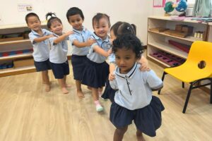 A group of young children playing a fun line-following game in a Montessori classroom, smiling and engaging in teamwork activities at Starshine Montessori.